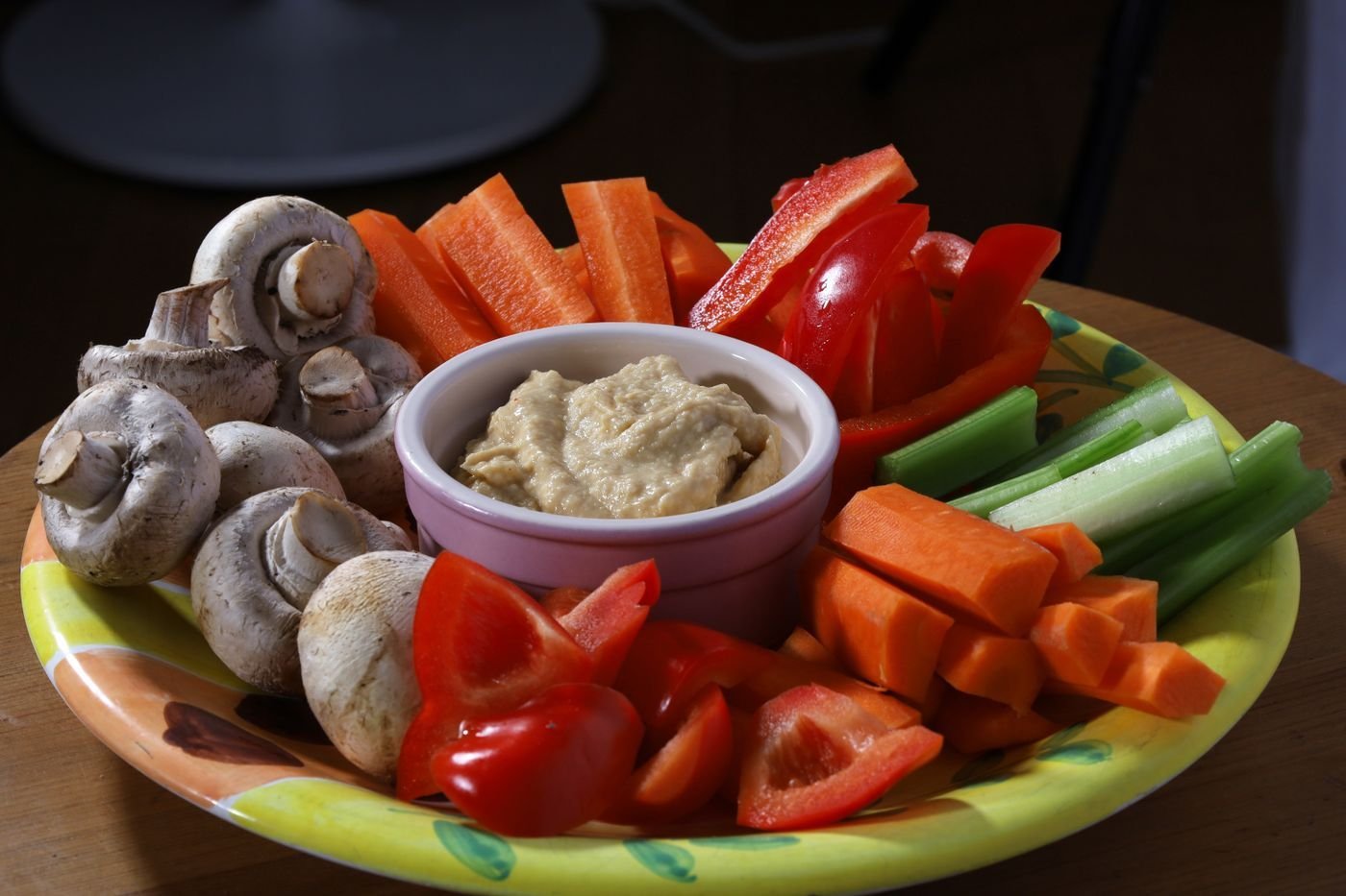 Platter of peppers, carrots, celery and mushrooms around a dip